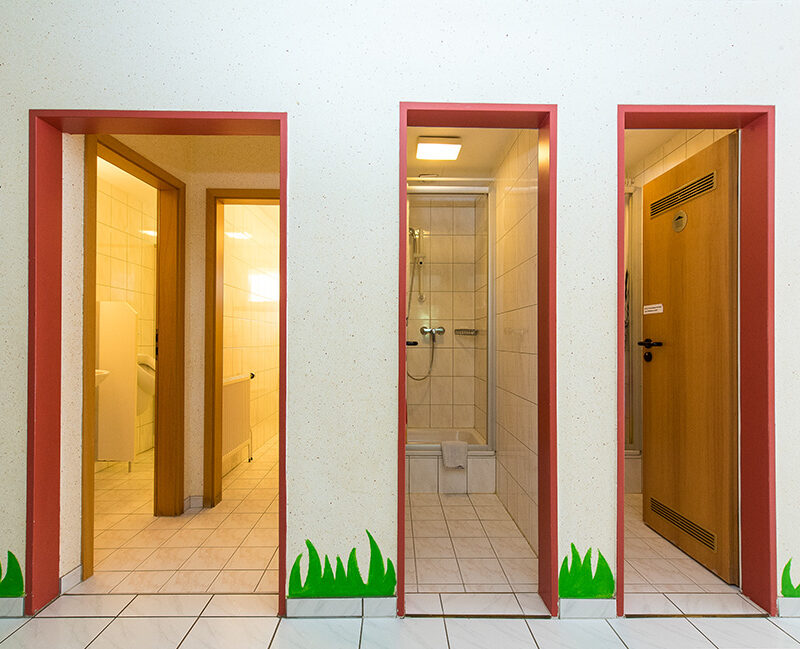 Drei Türen nebeneinander, die zu Toiletten und Duschen führen.